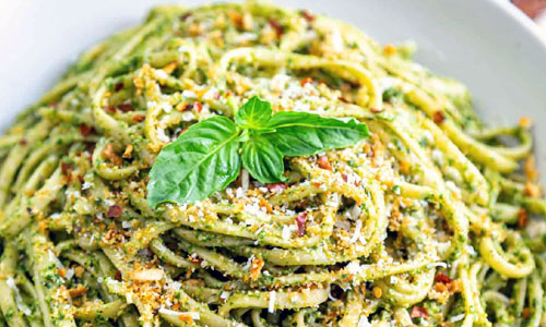Bowl of hot pasta with green pesto sauce